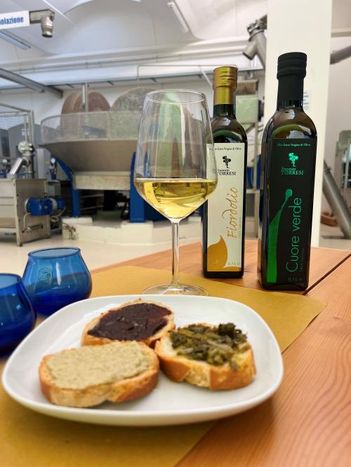 Visita guidata al frantoio con spiegazione del processo di spremitura delle oliveDegustazione di olio extravergine di oliva appena spremutoAperitivo rustico con bruschette e olio nuovo in frantoio marchigianoTris di bruschette con prodotti tipici locali e olio extravergineCalice di vino marchigiano accompagnato da specialità del territorioEsperienza autentica tra ulivi e sapori delle MarcheTavolata con assaggi di olio, vino e prodotti locali in frantoioOlio extravergine su pane casereccio durante la degustazioneMomento conviviale di aperitivo tra gli ulivi delle MarcheScoperta del gusto dell’olio novello con vini e prodotti tipici