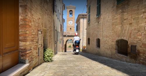 Vespa tour through the rolling hills of Le Marche.Medieval hilltop village with fortifications.Charming narrow streets in an old Italian town.Scenic view from a castle walkway.Village surrounded by nature, forests, and hills.Ancient castle with stone walls and towers.Panoramic road winding through the Marche countryside.