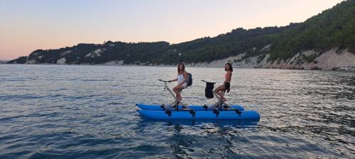 Persona in waterbike lungo la costa della Riviera del ConeroWaterbike su acqua cristallina con sfondo di scogliere biancheAlba vista dalla waterbike a largo del ConeroGruppo di persone in escursione waterbike vicino alla Spiaggia delle Due SorelleTramonto dorato sulla Riviera del Conero visto da una waterbikeVista panoramica della costa marchigiana da una waterbike in mareTour guidato in waterbike con paesaggi naturali mozzafiatoDettaglio di una waterbike galleggiante sull'acqua limpida del Conero